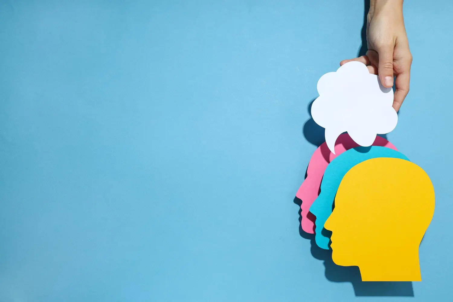 silhuertas de cabeças humanas empilhadas, uma amarela em por cima de uma azul que está porcima de uma rosa. acima delas na imagem tem um balão de pensamento com uma mão humana segurando.