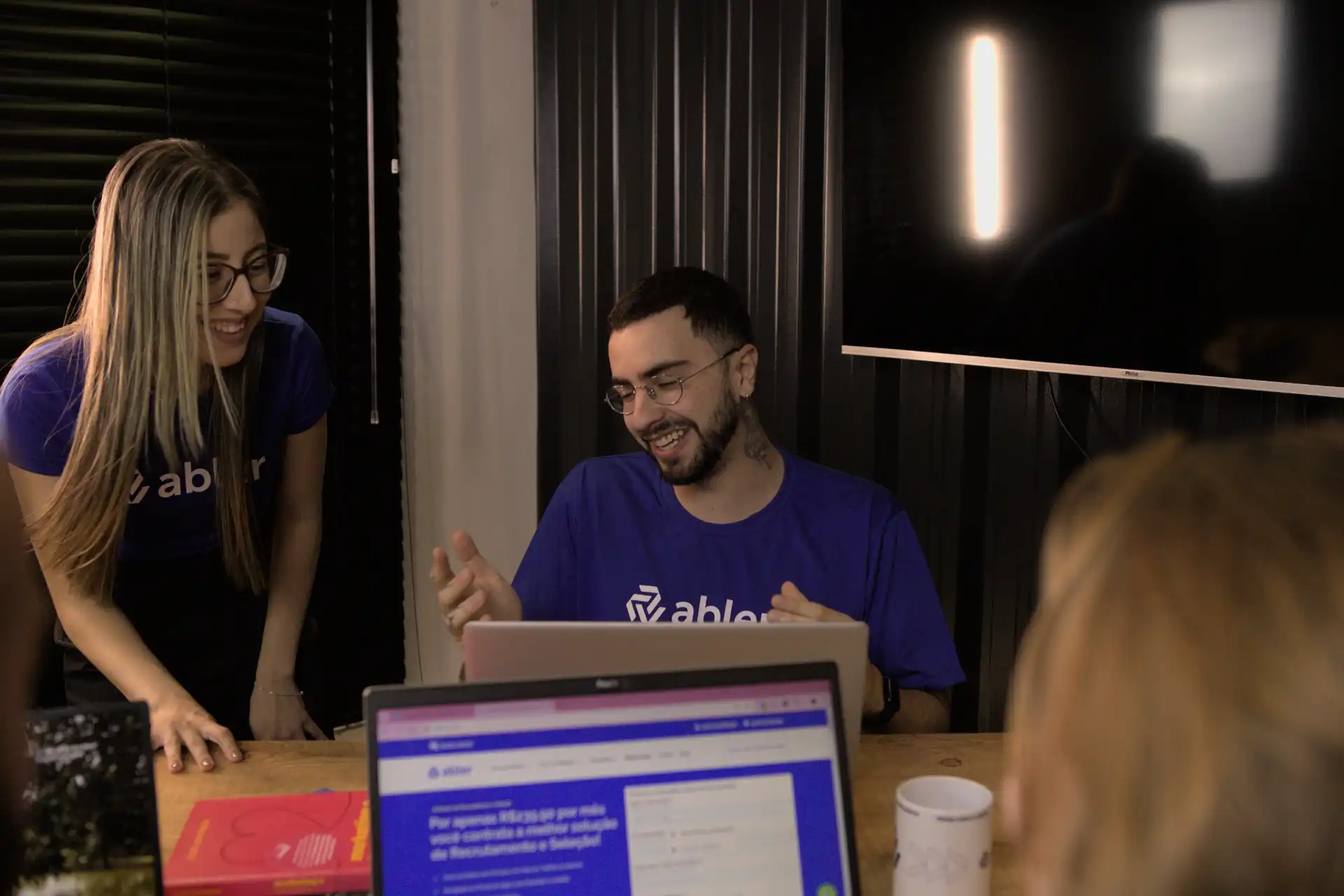 Equipe colaborando em reunião mostrando como anunciar vagas de emprego de forma eficiente usando tecnologia e comunicação efetiva.