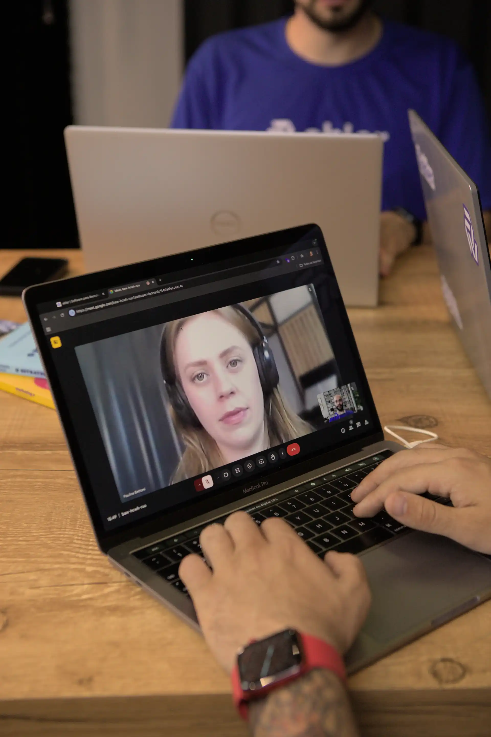 Reunião virtual mostrando técnicas de recrutamento e seleção, com pessoas usando computadores e fones de ouvido.