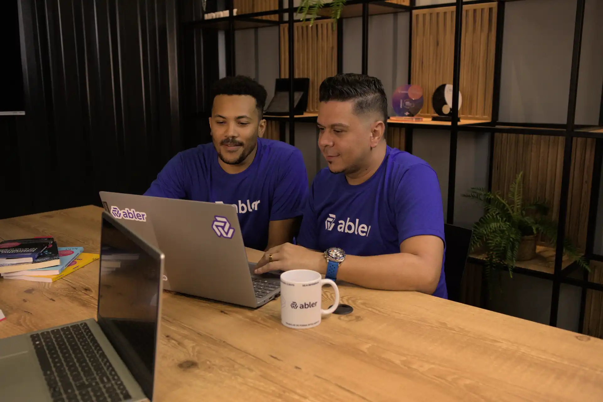 Dois homens colaborando em um projeto com um laptop em um ambiente de escritório moderno, ideal para um teste disc.