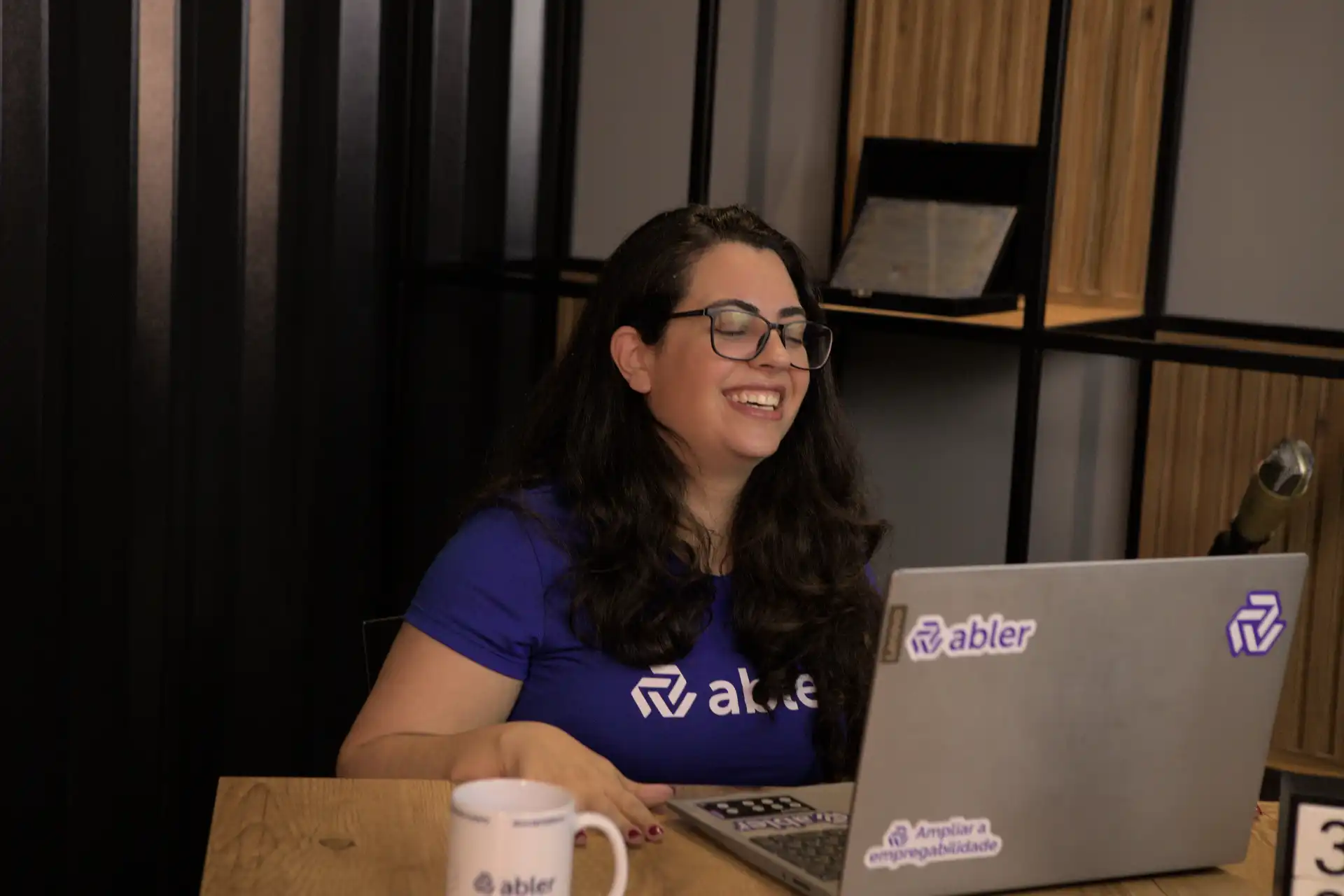Mulher sorrindo em frente ao computador, destacando o tema de fechamento de vagas no ambiente de trabalho.