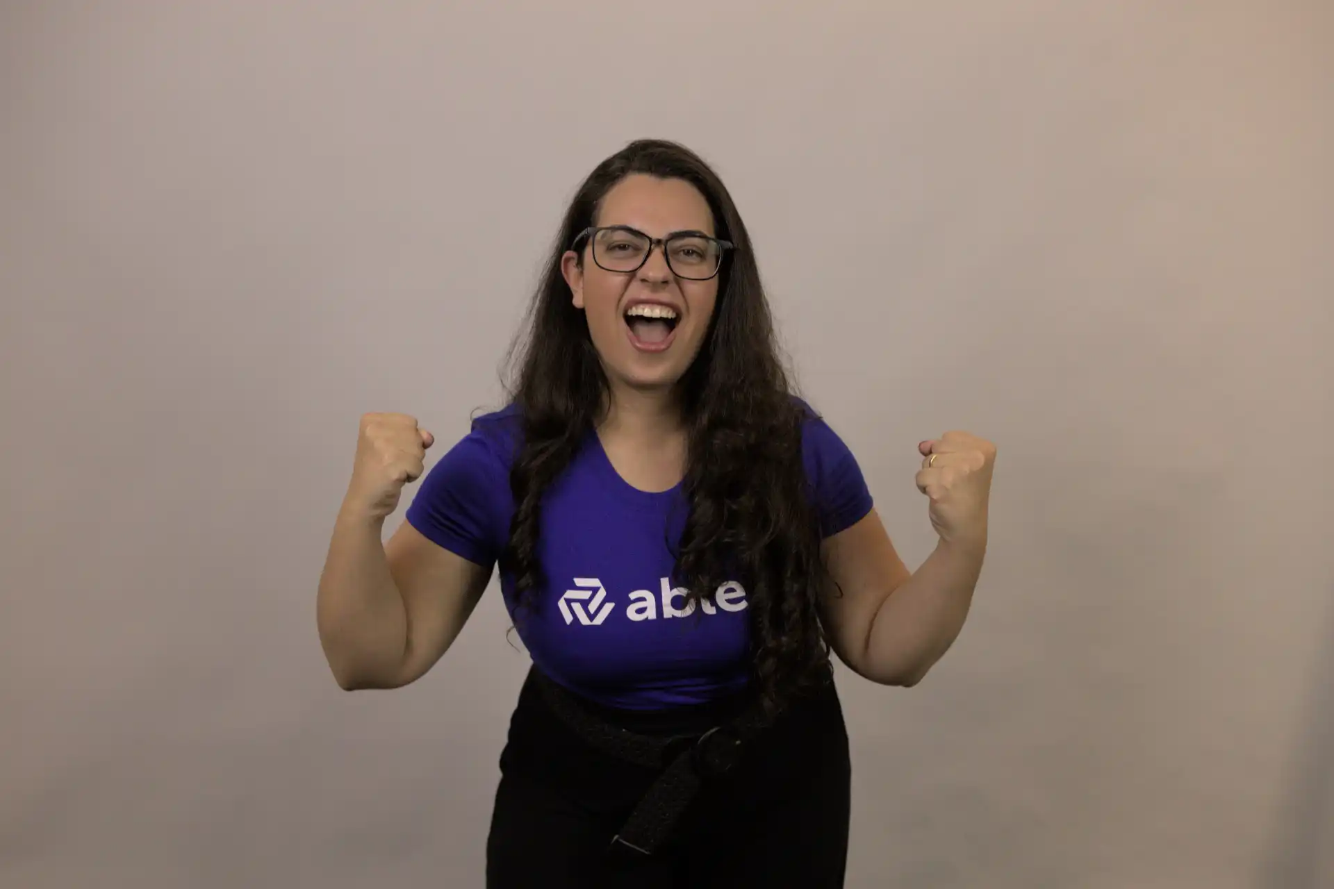 Mulher sorrindo e mostrando empolgação, vestindo uma camiseta azul da empresa ablee, transmitindo a ideia de mais valor em sua mensagem.