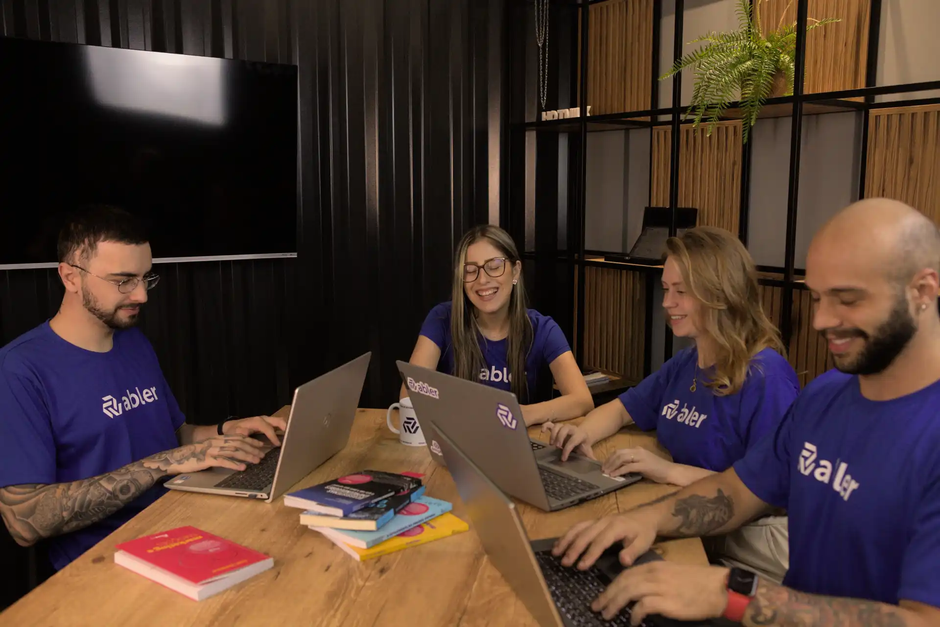 Imagem de um grupo de profissionais trabalhando juntos em um escritório, com laptops e materiais de estudo, focados na redução do turnover de clientes.