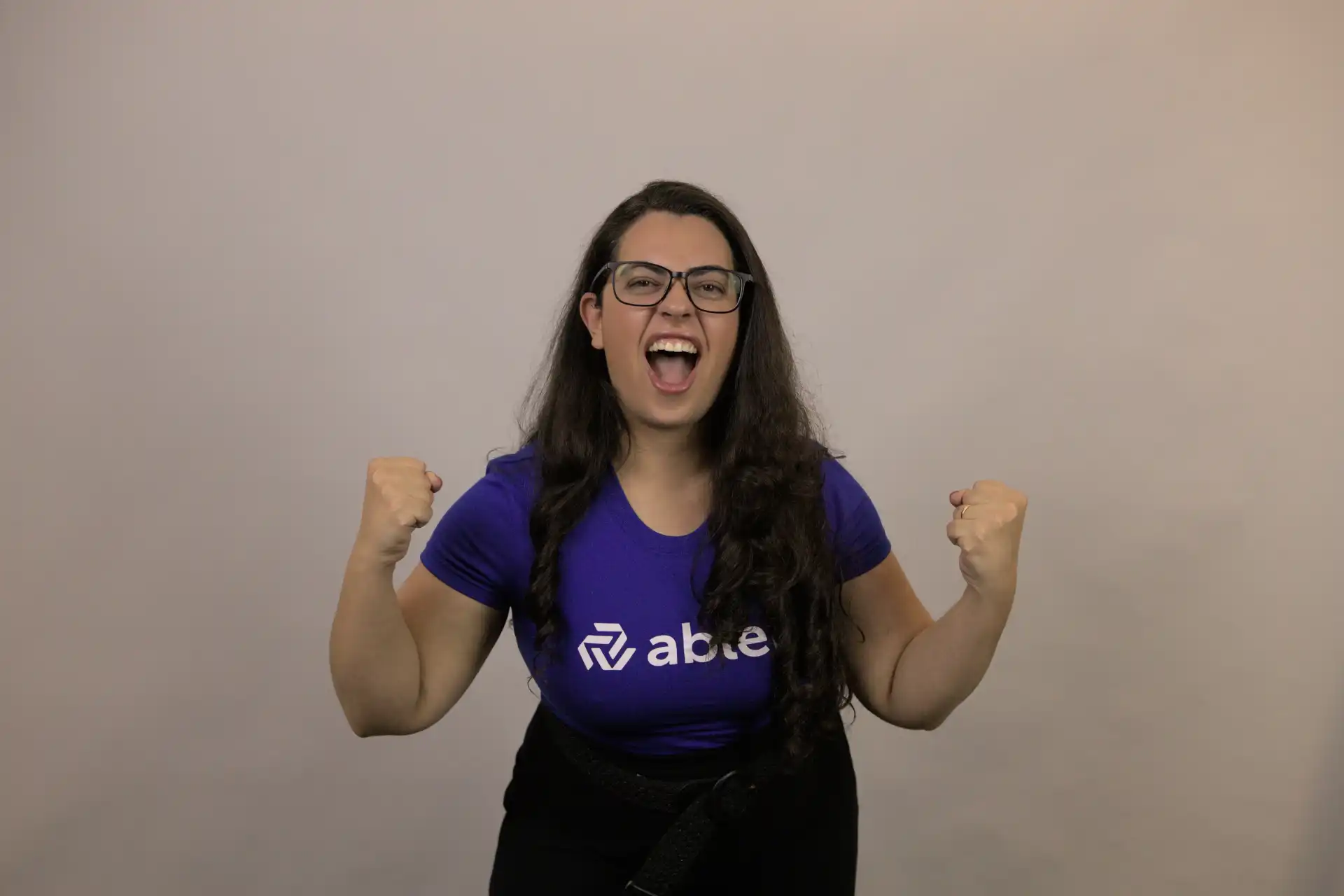 Mulher expressando empoderamento e alegria, representando a luta pela igualdade de gênero em um fundo neutro.