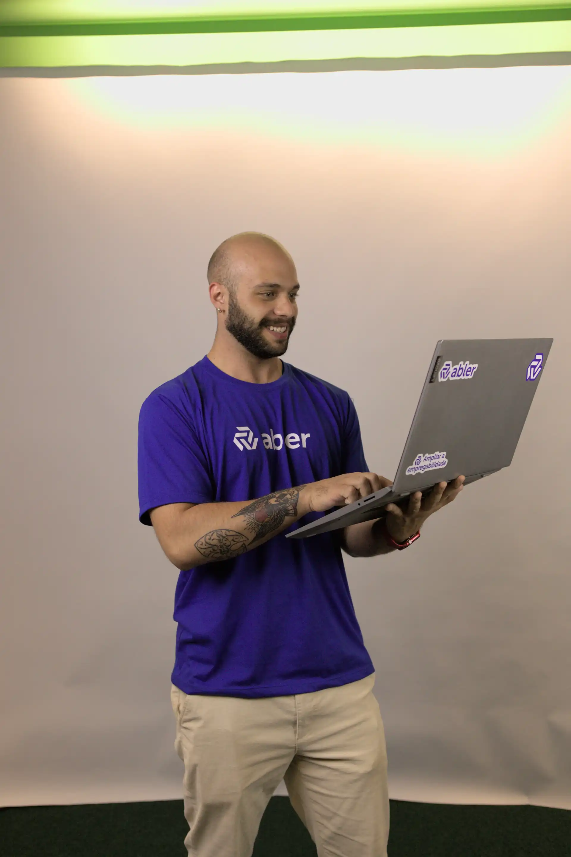 Homem sorridente usando laptop enquanto representa a marca Abler, simbolizando o volume de candidatos e a importância da tecnologia na seleção de talentos.