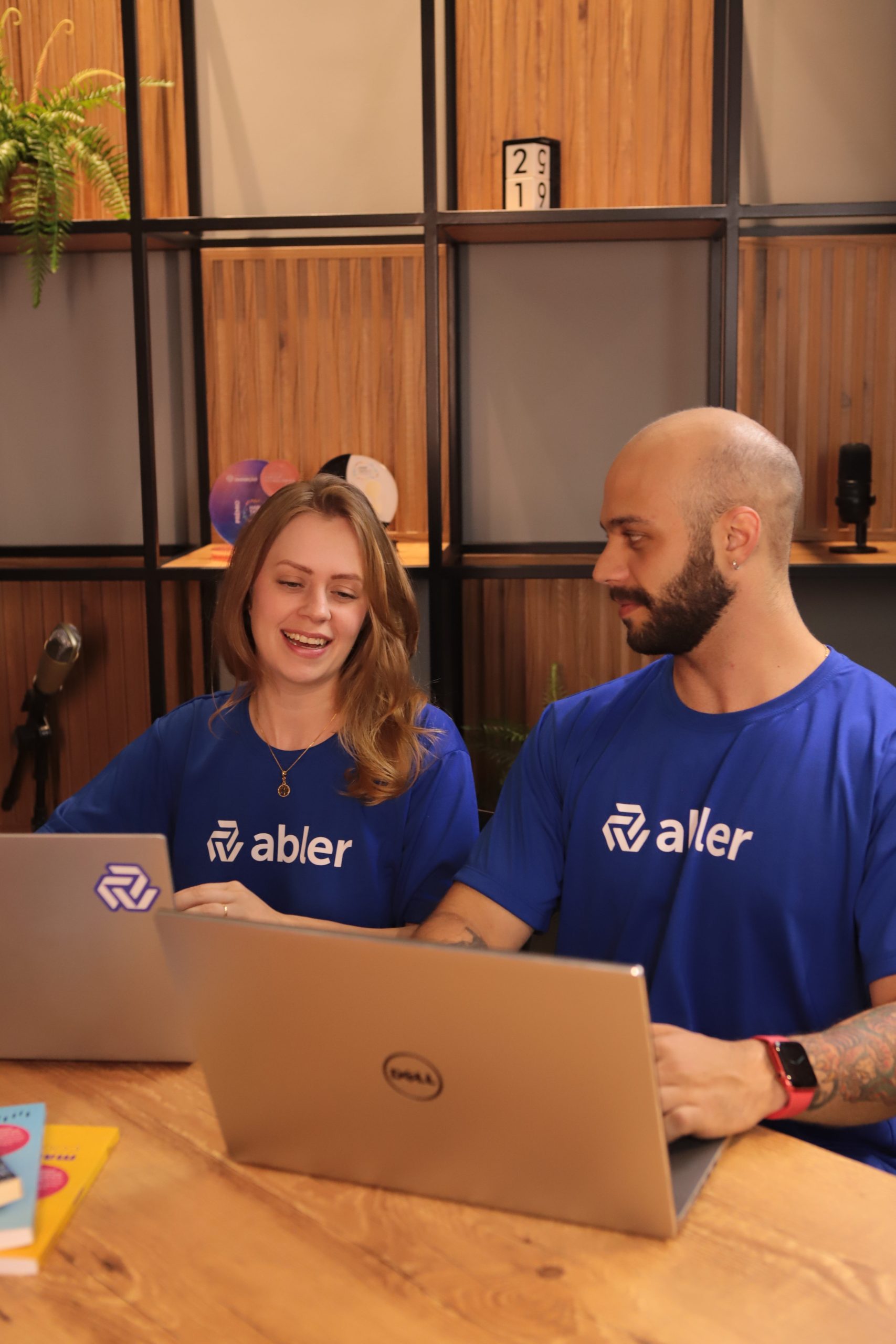 Dois profissionais da abler trabalham em notebooks durante uma reunião de recrutamento e seleção em ambiente corporativo. A imagem representa uma estratégia de sourcing ativo de talentos, com foco na busca ativa, identificação e engajamento de talentos qualificados para médias e grandes empresas, indo além da publicação tradicional de vagas.