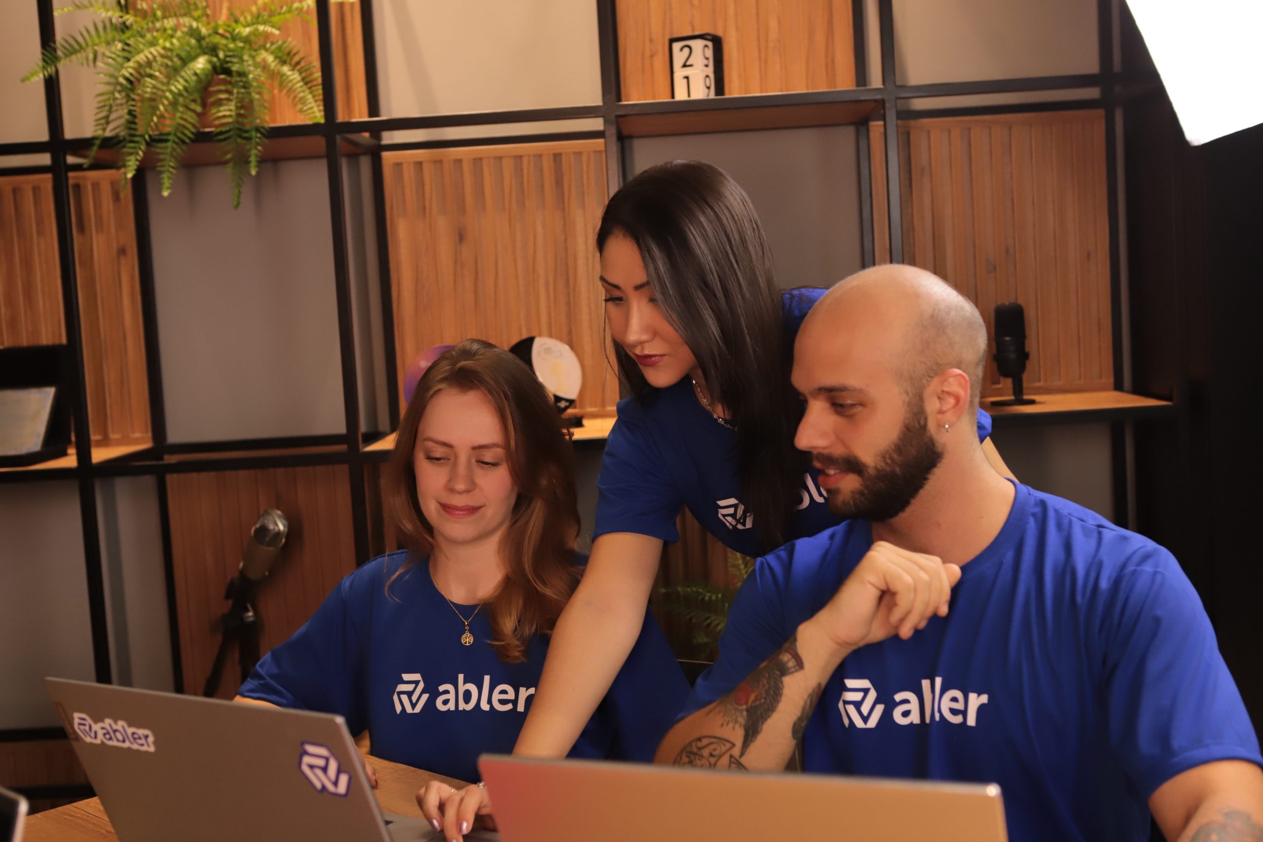 Três profissionais da abler colaboram em frente a notebooks durante uma atividade de recrutamento e seleção em ambiente corporativo. A cena representa a evolução dos processos de contratação diante da escassez de talentos, destacando o uso de um sistema de recrutamento ativo para apoiar desde a triagem de candidatos até estratégias de sourcing ativo, tornando a operação mais eficiente, previsível e orientada à atração de talentos qualificados.